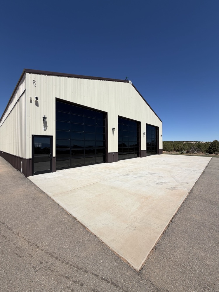 Close exterior view of three full-view glass commercial garage door bays with fresh concrete apron