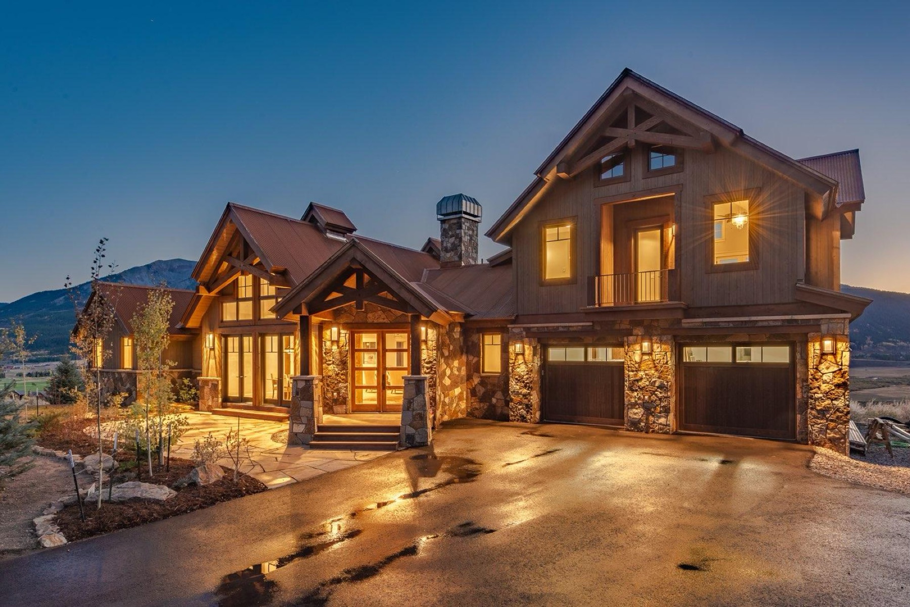 A custom Kooler timber-and-wood garage door home lit up at dusk on the Western Slope