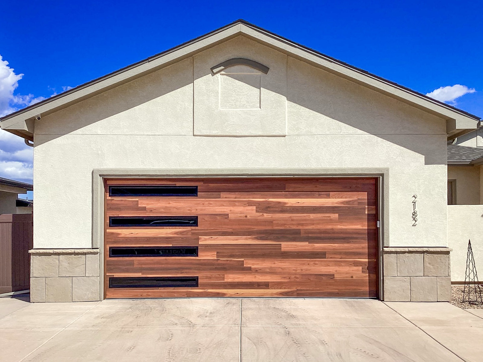 Contemporary wood garage door with offset frosted-glass panels on a stucco home