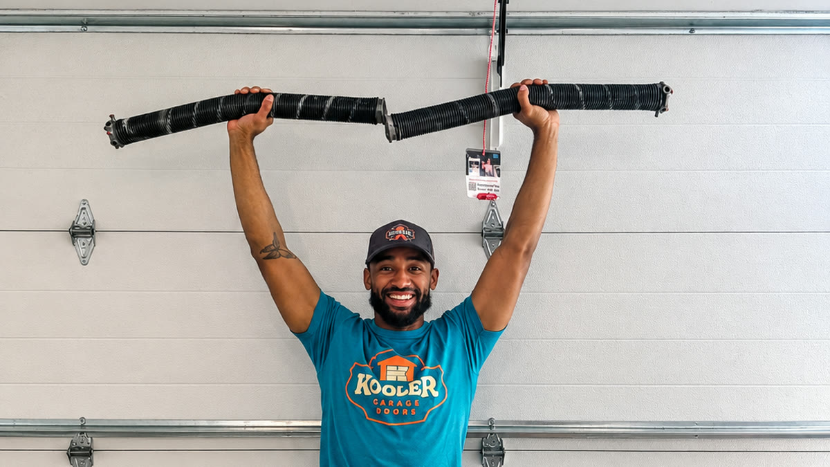 Elijah, a Kooler Garage Doors Kraftsman, holding up a pair of undersized torsion springs that came off a garage door