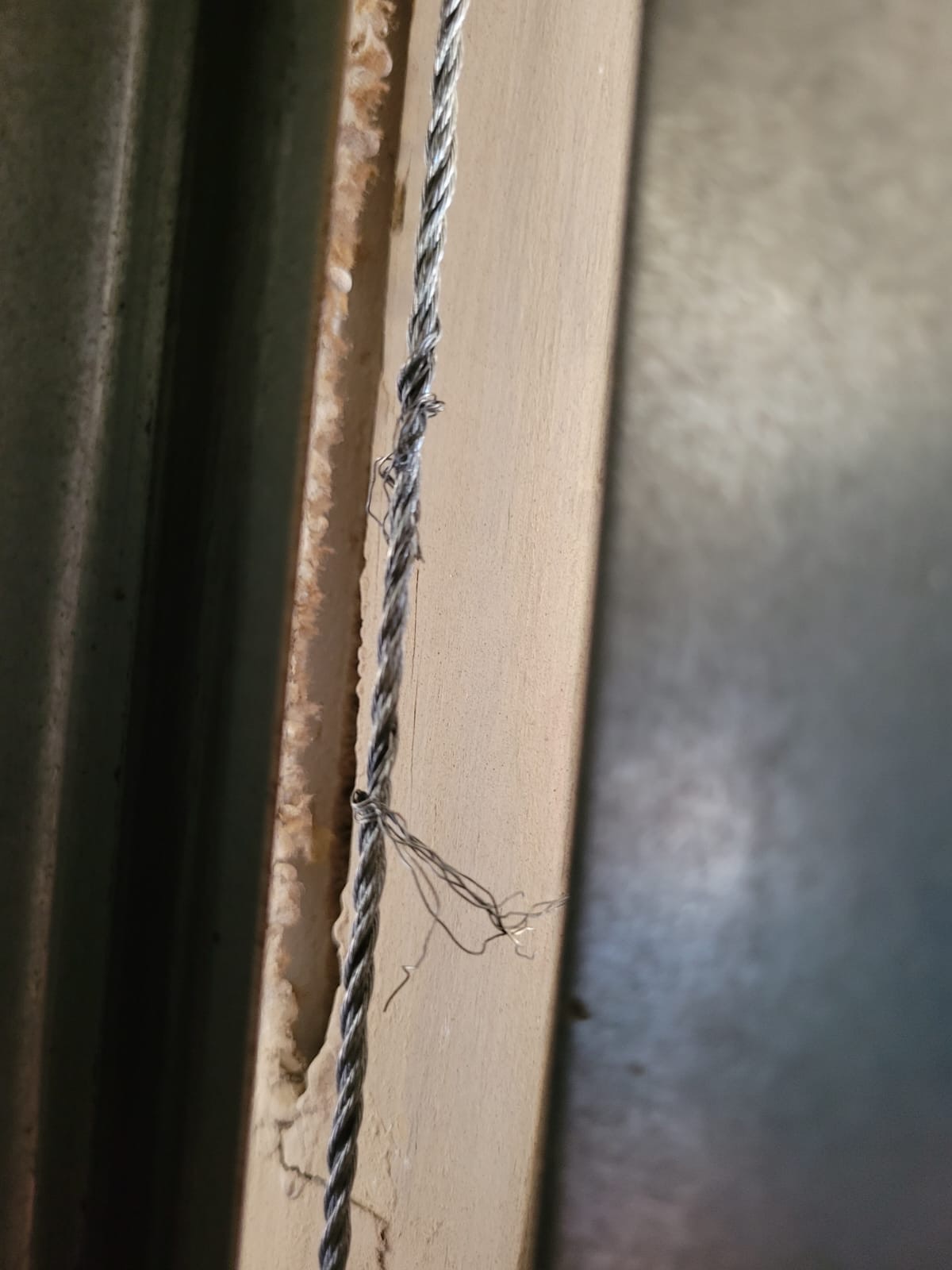 Close-up of a frayed garage door lift cable caught before failure