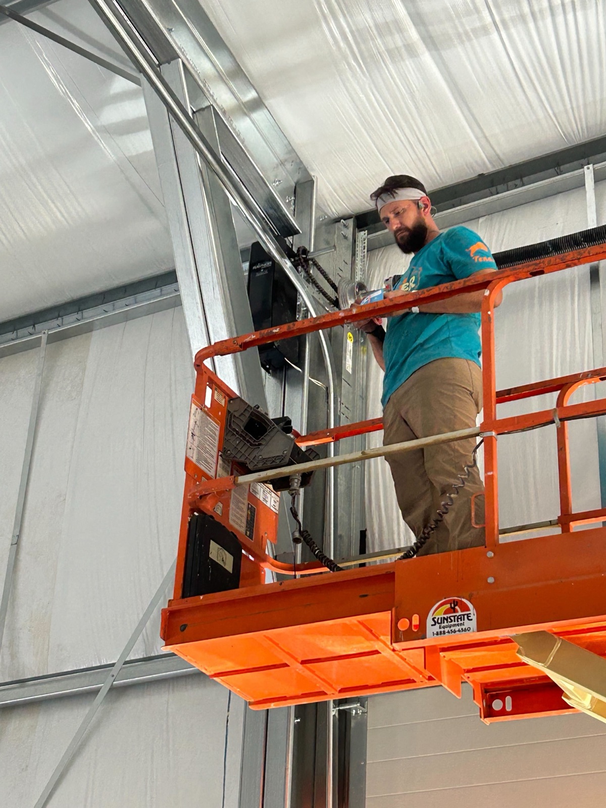 A Kooler Kraftsman on a lift installing a commercial high-bay garage door