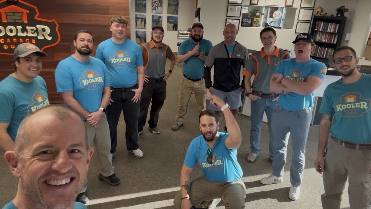 The Kooler Garage Doors Krew together in the Grand Junction shop, owner Matt Kuehlhorn in front, under the Kooler sign