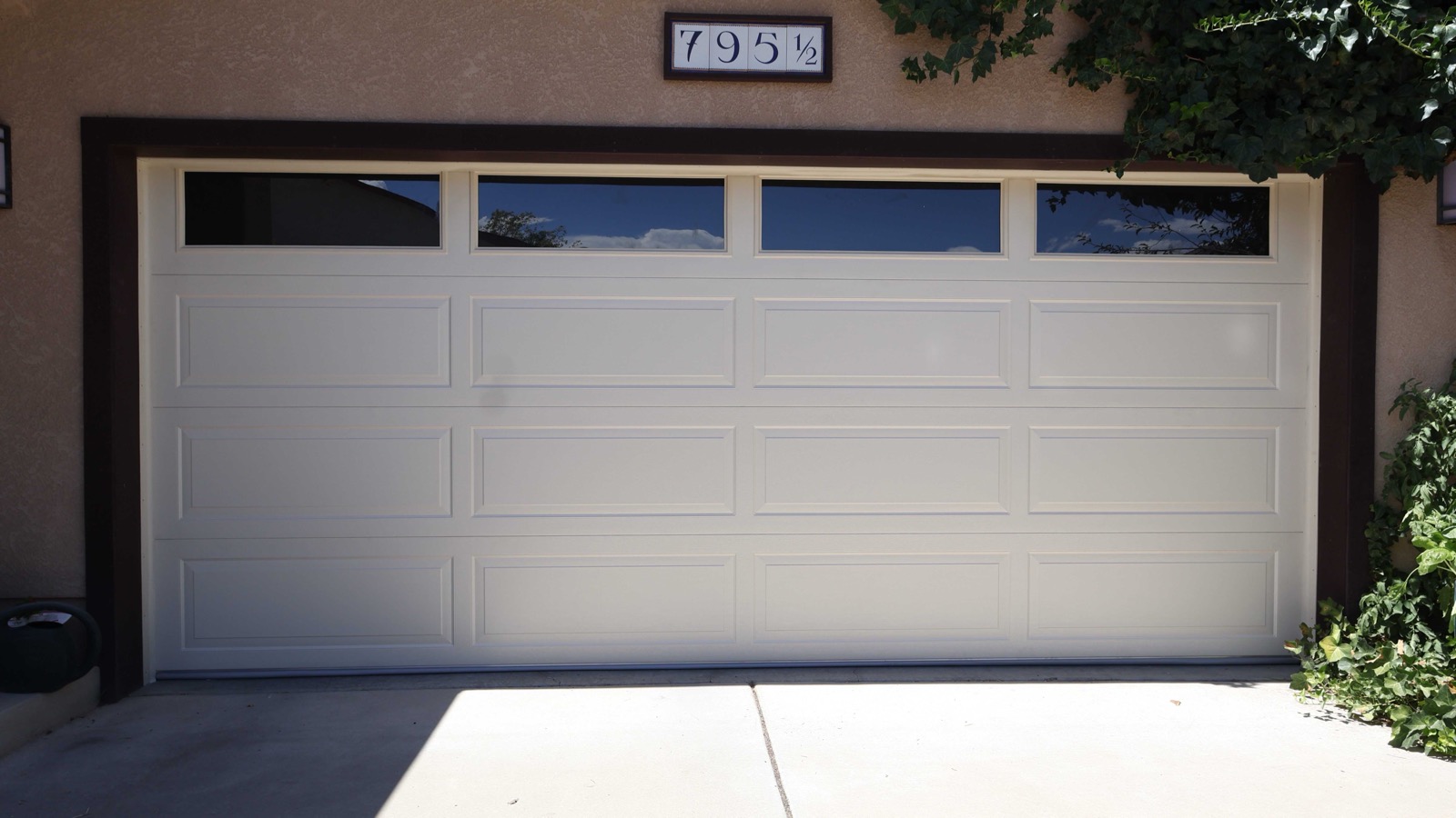 A white long-panel garage door with a row of windows, closed on a Grand Valley home
